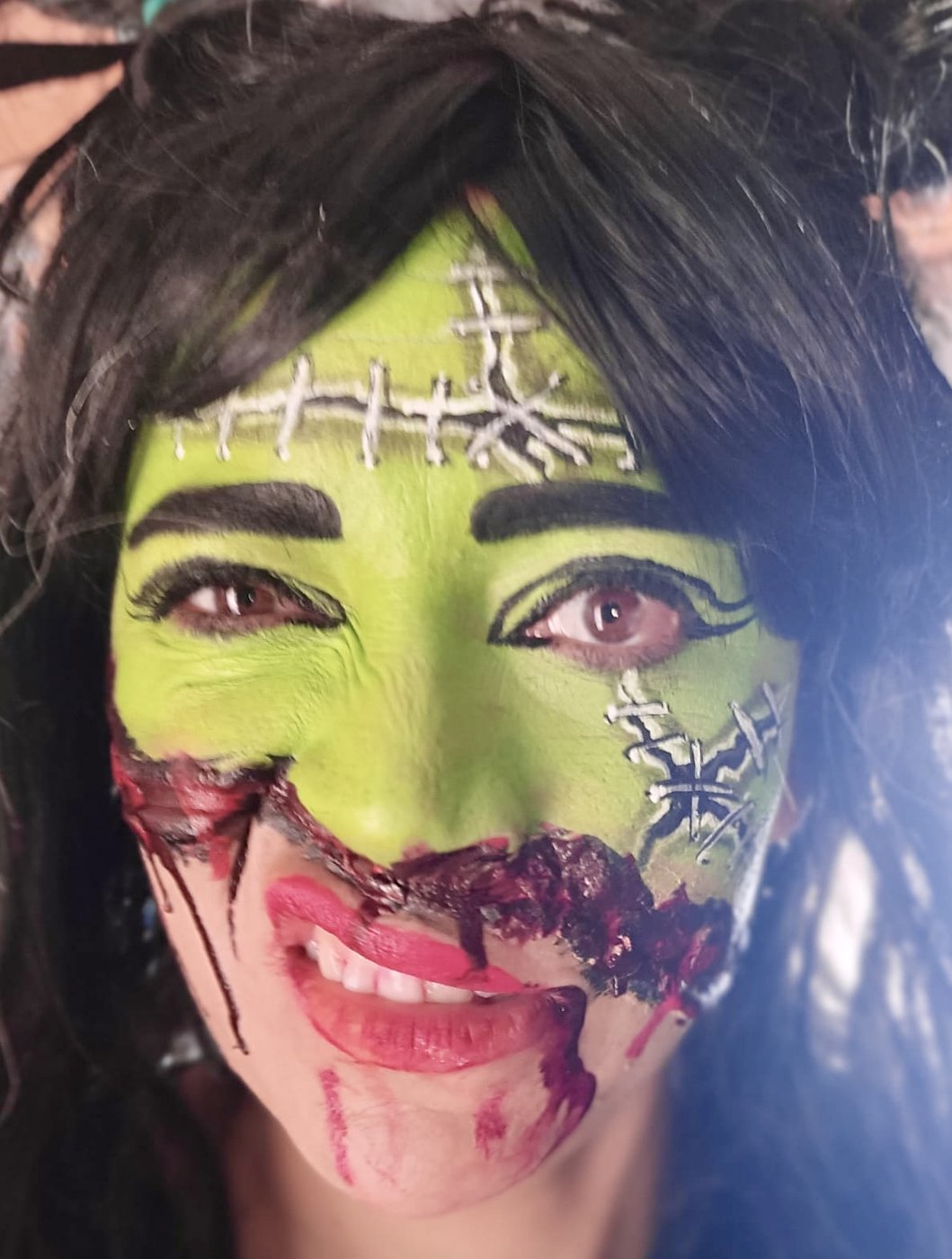 Maquillaje FX zombie verde estilo Frankenstein con suturas y herida sangrante