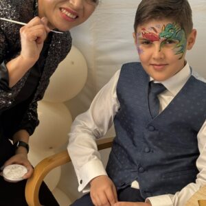 Lucy maquillando dragón a un niño en evento