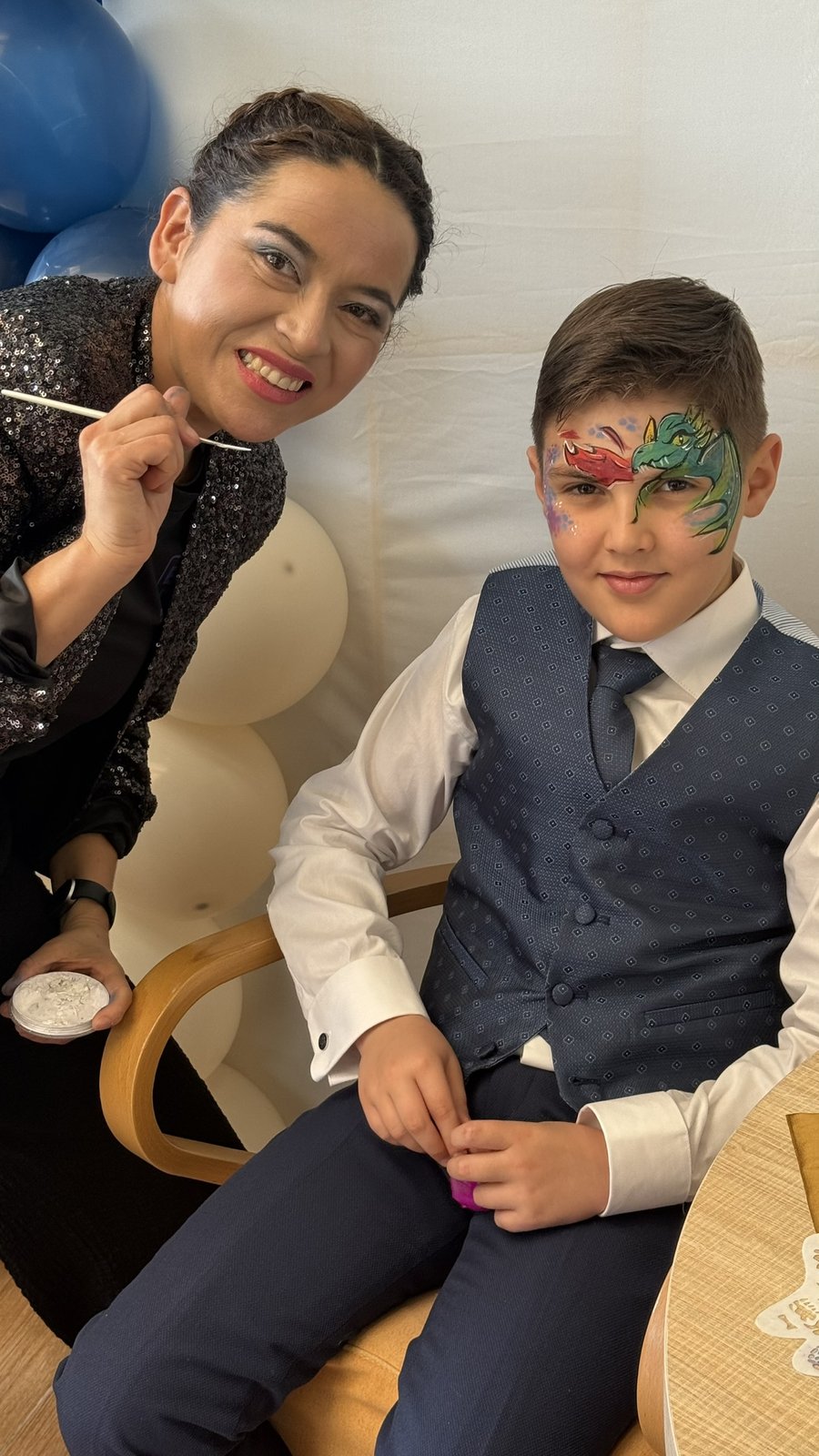 Lucy maquillando dragón a un niño en evento